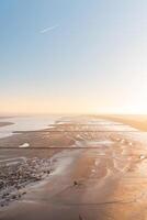 Drying shore at low tide of Plaat van Walsoorden at Ossenisse radar in the southern Netherlands under the brilliant orange-yellow glow of sunrise photo