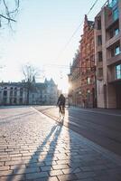 hombre corriendo a trabajo en su bicicleta durante amanecer en el ciudad centrar de gante, Bélgica. bicicleta como el principal medio de transporte. ecológico Ingenieria foto
