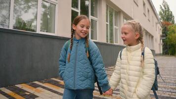 Two little girls friends sisters classmates walk going street city outside hanging out meeting talking chatting discussing sharing news communicate children kids learners dialogue conversation speak video