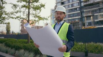 Pensive thoughtful puzzled worker repairman man in city urban development building looking at blueprint paper explore plan male architect architecture business construction engineer in helmet and vest video