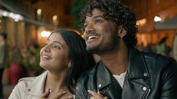 Happy laughing smiling Indian boyfriend man and Arabian girlfriend woman couple travelers tourists in new city contemplate strolling walking cuddling walk at evening night street architecture explore video