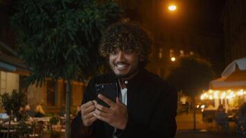 Indisch Arabisch latino Amerikaans Mens Holding smartphone mobiel telefoon mobiele telefoon telefoon op zoek Bij scherm verheugen zege mooi zo nieuws geluk vreugde succes vieren winnen verbazingwekkend schreeuwen opwinding mannetje vent video