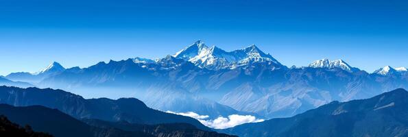 Mountain range with snow, clouds, and electric blue sky in background photo