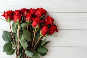 A bouquet of red roses adorns a white wooden table photo