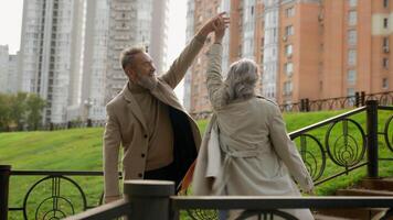 spensierato maturo caucasico coppia nonni famiglia danza romantico anniversario insieme danza nel città parco contento 60s anziano più vecchio donna uomo in movimento all'aperto amorevole contento maschio femmina partner nel amore video