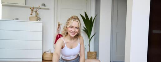 retrato de joven mujer personal yoga instructor, grabación rutina de ejercicio a hogar, utilizando digital cámara a vlog su ejercicios, utilizando caucho estera foto