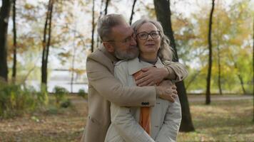 Retired mature old man hug woman from behind affectionate husband embrace wife cuddle romance tender relationship love Caucasian family couple male female bonding hugging in city autumn park outdoors video