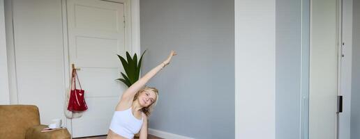 retrato de joven mujer personal yoga instructor, grabación rutina de ejercicio a hogar, utilizando digital cámara a vlog su ejercicios, utilizando caucho estera foto