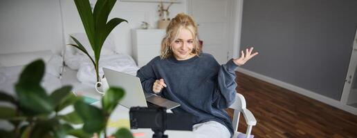 retrato de joven mujer, estilo de vida bloguero, grabación vlog acerca de su vida y diario rutina, sentado en frente de computadora portátil, hablando a seguidores, sentado en su habitación foto