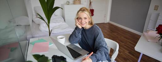 retrato de joven mujer distancia aprendiendo, trabajando desde hogar con computadora portátil, haciendo notas, estudiante estudiando en remoto, haciendo en línea curso foto