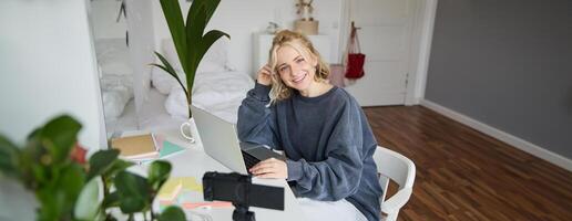 Portrait of young beautiful woman, social media influencer, recording tutorial, lifestyle vlog, creating content in her room using digital camera photo