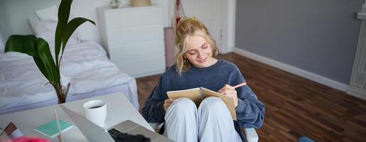 Portrait of cute, smiling young social media content creator, girl records on digital camera and stabiliser, holds notebook, talks to audience, vlogging in her room photo