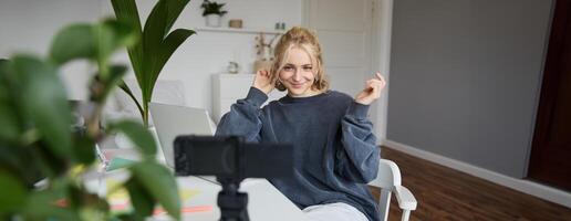 retrato de joven mujer, estilo de vida bloguero, grabación vlog acerca de su vida y diario rutina, sentado en frente de computadora portátil, hablando a seguidores, sentado en su habitación foto