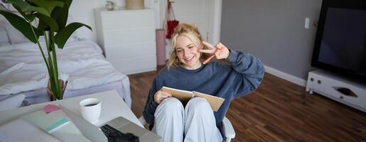 retrato de sonriente linda mujer, estilo de vida bloguero, se sienta en su habitación con diario diario o planificador, registros en digital cámara, crea contenido para social medios de comunicación acerca de diario rutina foto