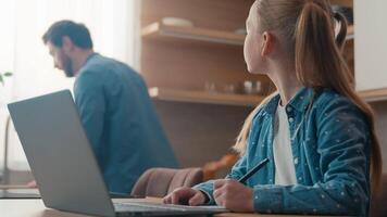 família às casa homem Papai ocupado às cozinha pequeno filha criança criança menina escrever tarefa dever de casa estudante problema problema Educação pai Socorro e-learning computador portátil computador ajudando com difícil questão video