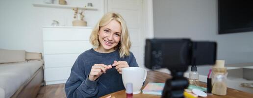 Young charismatic beauty blogger, teenage girl records of her applying mascara, reviewing makeup products for her lifestyle vlog, vlogging for social media account photo