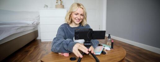 retrato de joven Adolescente niña en su habitación, grabación un vlog, diario estilo de vida para social medios de comunicación, Internet hombre de influencia publicidad producto en línea, hablando a el cámara, sentado en el piso foto