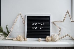 NEW YEAR NEW ME text on black letter board with cozy minimalistic handmade Christmas decor. New year aims resolutions. Low key festive Planning and setting goals concept photo