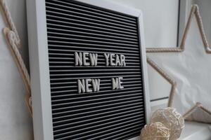 NEW YEAR NEW ME text on black letter board with cozy minimalistic handmade Christmas decor. New year aims resolutions. Low key festive Planning and setting goals concept photo