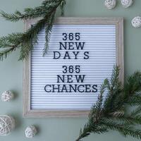 365 NEW DAYS 365 NEW CHANCES text on white letter board on green background with Christmas decor. New year aims resolutions. New year me concept photo