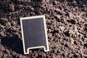 Blank Black billboard against green field garden. Empty mockup template Blackboard label at farm land. Copy space banner for your text. Agricultural landscape advertisement sample photo