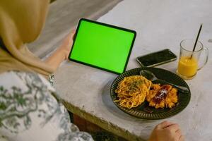 Green Screen iPad or Tablet with Cafe Ambiance and Food on Table photo