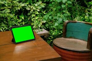 verde pantalla ipad o tableta en de madera mesa con verde plantas antecedentes foto