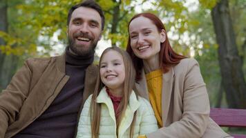 heiter Familie zusammen glücklich Lachen Mann Vater Frau Mutter Kind Kind Mädchen wenig Tochter draußen im Park Sitzung auf Bank lächelnd Zuneigung Kindheit Papa Mama Baby Lachen Lächeln beim Kamera Porträt video