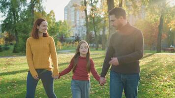 Happy Caucasian family holding hands walking in park talking parents child talk speaking conversation walk go in city outdoors nature weekend holiday spend time together sunny weather autumn spring video