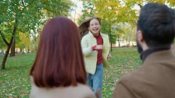 caucasico contento famiglia fine settimana vacanza natura all'aperto nel città autunno parco bonding amore indietro Visualizza amorevole genitori madre padre catturare abbraccio coccole poco bambino ragazzo ragazza figlia in esecuzione abbracciare sorridente video