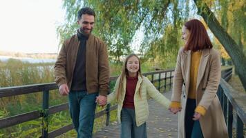 Caucasian happy family weekend holiday at nature outdoors laughing smiling in city autumn park together talking friendly daughter girl child kid go walk parents mother father holding hands walking video