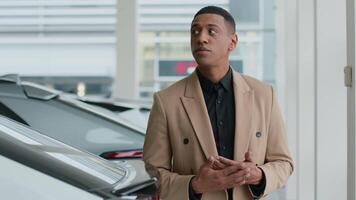 Thoughtful pensive guy male businessman African American man client buyer think choose new automobile in auto salon store thinking puzzled customer think ponder dream buy rent car decision loan credit video