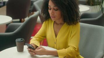 infeliz africano americano mulher dentro cafeteria segurando cabeça Smartphone Móvel telefone celular notificação SMS mensagem erro perda chateado fêmea problema dificuldades demolir estressado triste menina cansado problema video