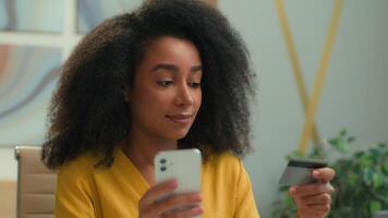 africano americano étnico o negócio mulher menina cliente usando Móvel telefone Comprar pagar crédito cartão Internet banco sorridente fêmea empresária escritório Gerente executivo conectados compras dinheiro Forma de pagamento comércio eletrônico video