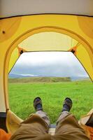 Man lying in tent with a view of mountain photo