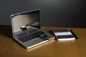 Phone, laptop and empty notebook on the desk photo