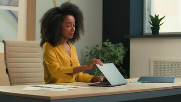 africano americano negocio mujer mujer de negocios niña terminar remoto trabajo logrado computadora proyecto final trabajando día cerca ordenador portátil sonriente hembra gerente empleado estar arriba salir oficina lugar de trabajo Vamos lejos video