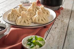 Close up to Caucasian khinkali dumplings dish served on plate. Background with ingredients and scattered spices photo