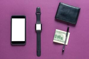 Business concept. Top view of dollars, watch, smartphone on color background photo