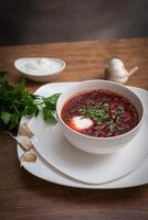 Red borscht soup with dill in white bowl. photo