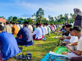 padang pariaman, Indonesia - abril 10, 2024. musulmanes realizar eid al-fitr oraciones en el campo en kayutanam, padang pariaman regencia foto