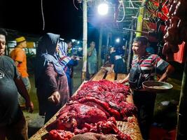 Pariaman, Indonesia - April 9, 2024. A woman buys meat at the livestock slaughtering market, a tradition before Eid al-Fitr in Pariaman City photo