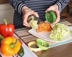Woman pulls sliced vegetables from container of vegetable chopper in kitchen. photo