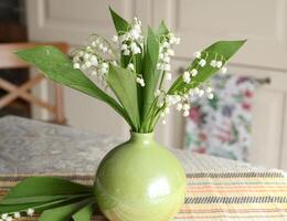 Bouquet of lilies of valley in green vase indoor on table photo