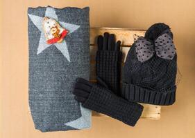 Set of winter cap, scarf and gloves on colored background photo