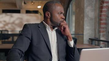 omtänksam tänkande afrikansk amerikan vuxen chef manlig arbetstagare kille tror lösning fundera beslut hitta svar komma upp aning planen i kontor etnisk affärsman man arbetsgivare skriver bärbar dator skapa företag video