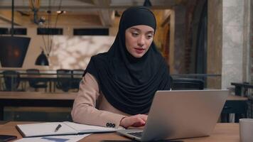 Arabian businesswoman muslim islamic woman in hijab female manager freelancer student typing project on laptop computer at coworking office remote work online studying happy joyful business girl smile video