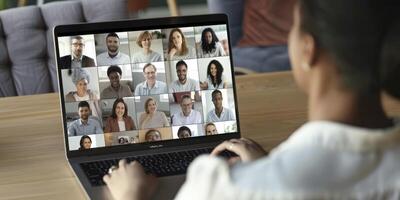 a person is sitting at their laptop, with multiple people on the screen having an online meeting or conference call photo