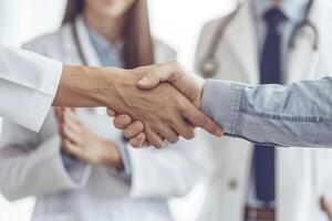 Doctor shaking hands with his patient while the nurse is smiling in front of them photo