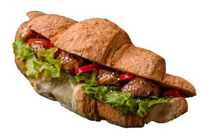 Delicious fresh crispy croissant with chicken or beef meat, lettuce, tomatoes, spices and sauce photo